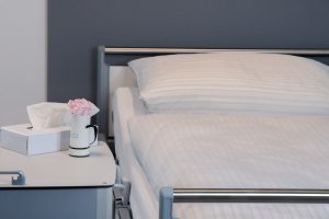 Das Bild zeigt ein Patientenbett mit Nachttisch